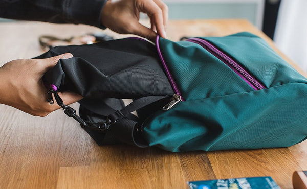 A person putting an organizer pouch in the main compartment of an Icon.
